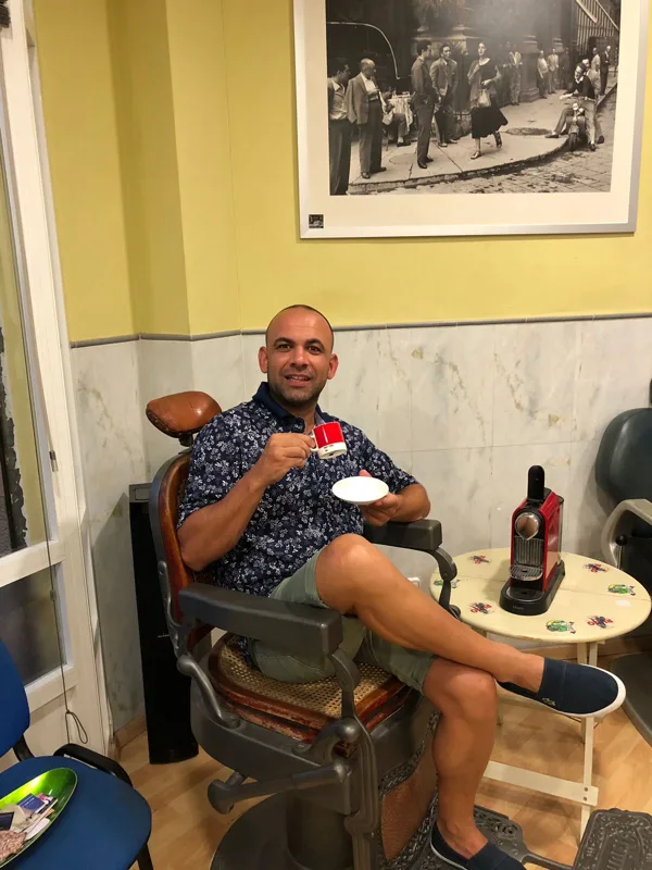 Jordi Valera assegut a una cadira de barber antiga amb un cafè a la mà